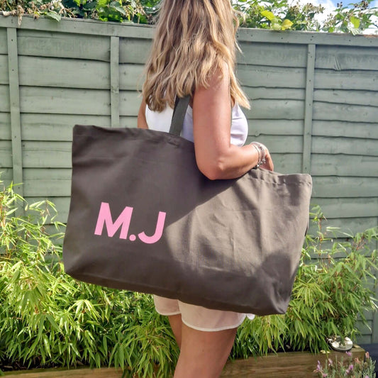 A lady with an extra large olive bag with a baby pink initials