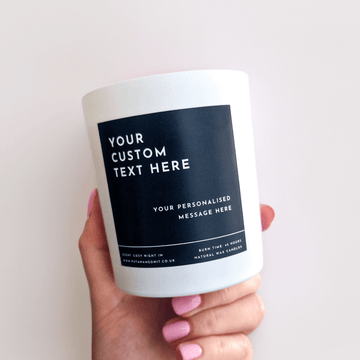 A hand holding a candle. White jar and black label give that elegant and minimalistic feel. The candle label can e personalised with a text of your choice. Bold text on top and smaller text at the bottom